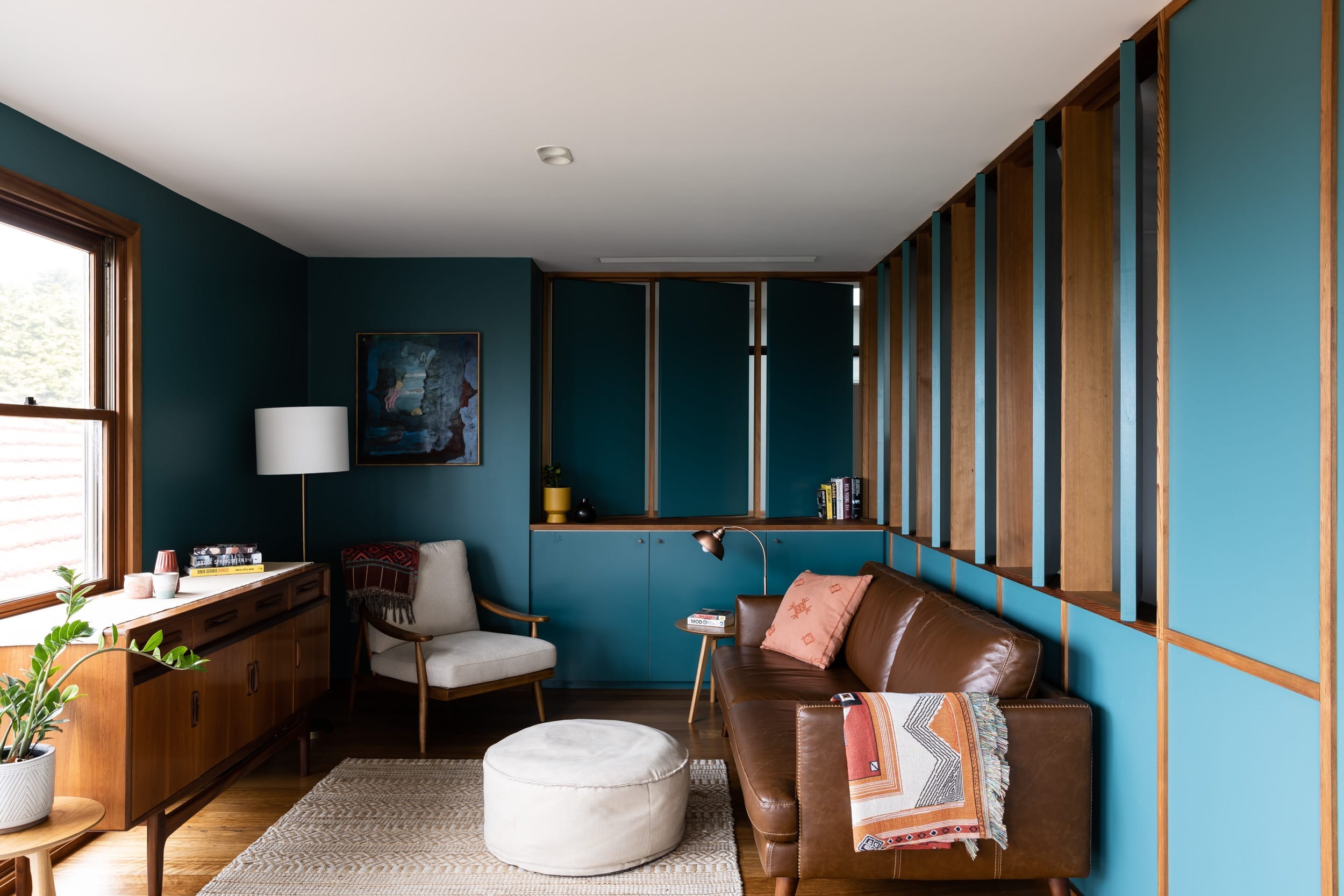 Mid century modern inspired living room with blue painted interior and timber accents