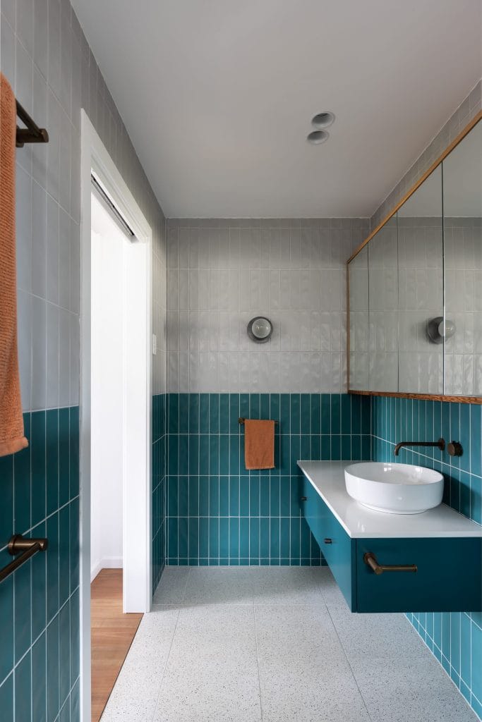 A modern retro ensuite with teal and white tiles and a teal vanity by YourBuild Construct