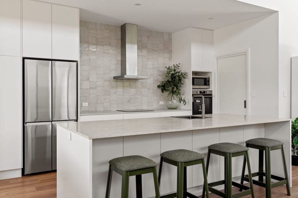 Modern white kitchen with olive green bar stools and stainless steel appliances
