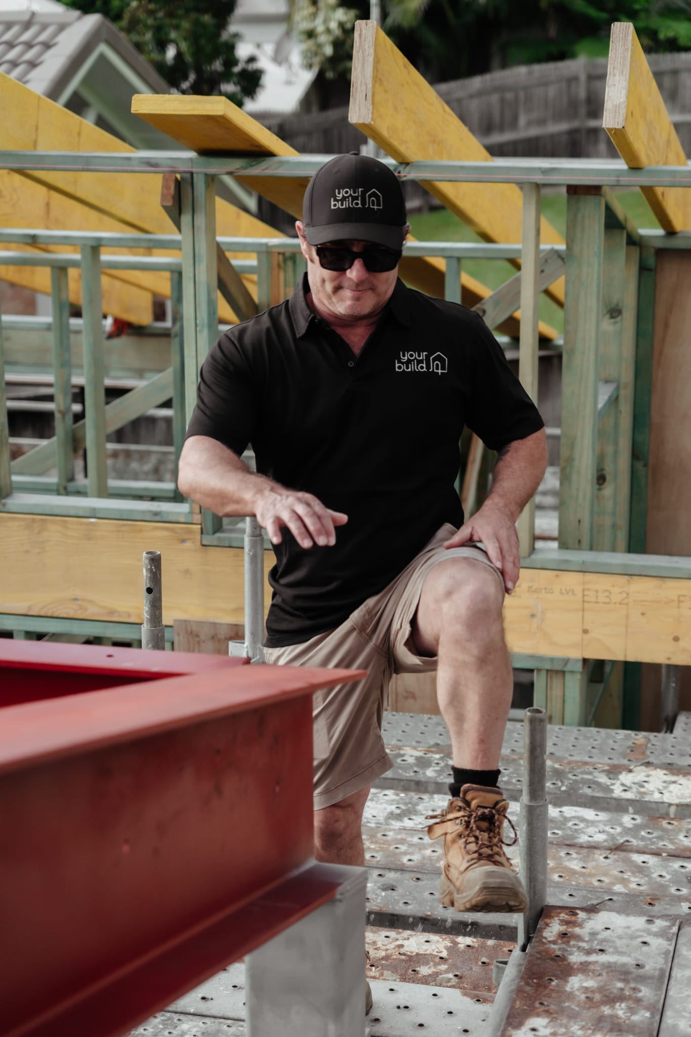 A YourBuild Construct team member on a building site with timber and steel framing
