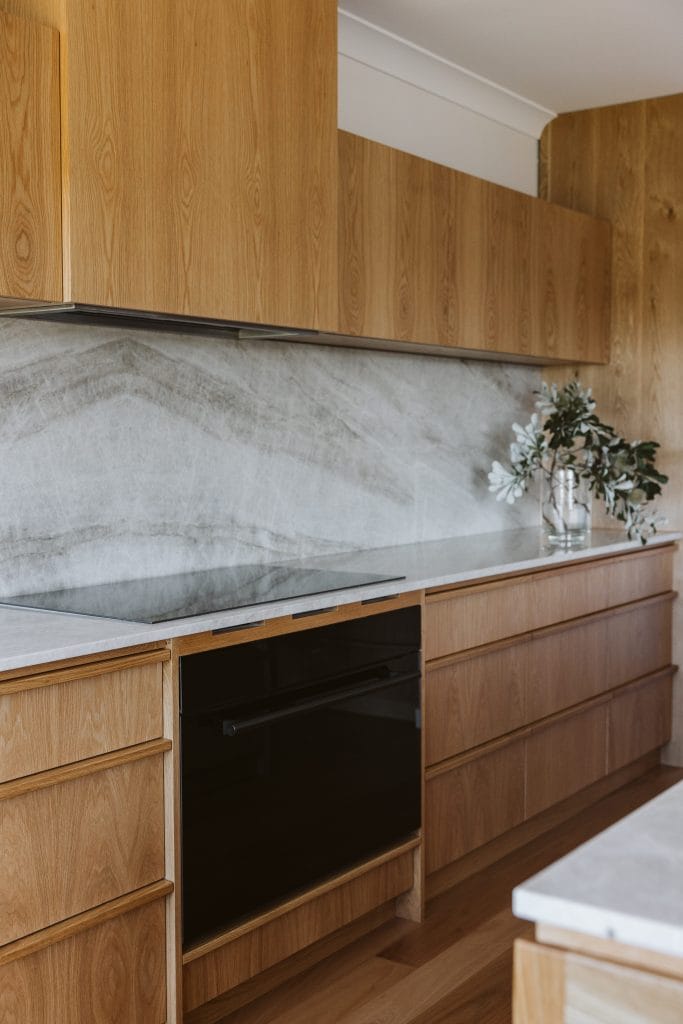 A mid-century modern kitchen renovation with timber cabinets and induction stove top and integrated rangehood