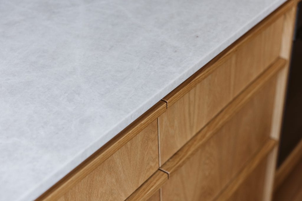 Detail of floating grey kitchen benchtop and timber cabinetry