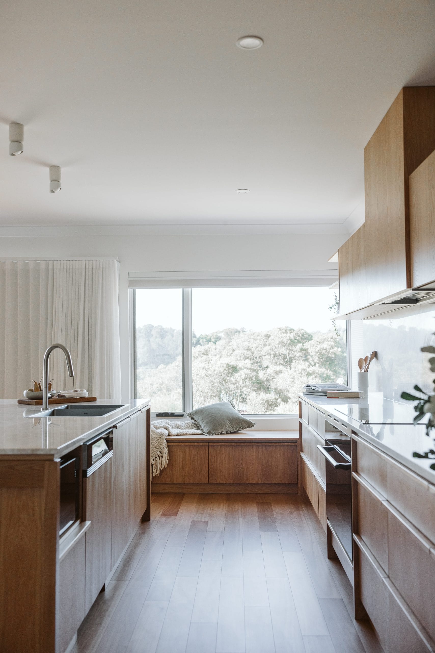 View through a timber kitchen to a window seat with a view of tree tops