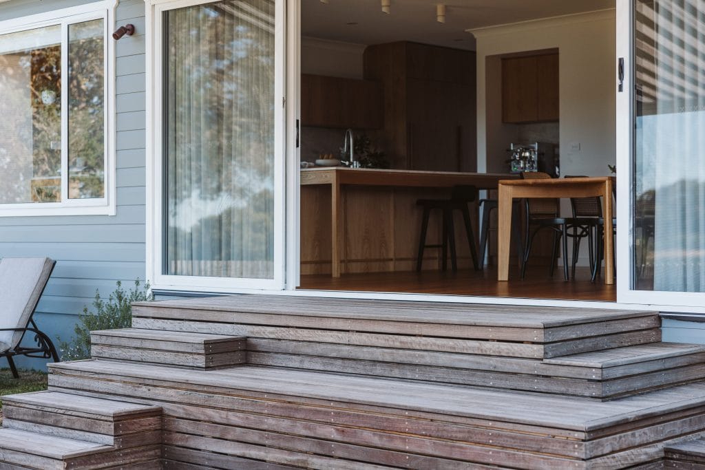 Rear sliding doors opening from the kitchen and dining area onto timber steps