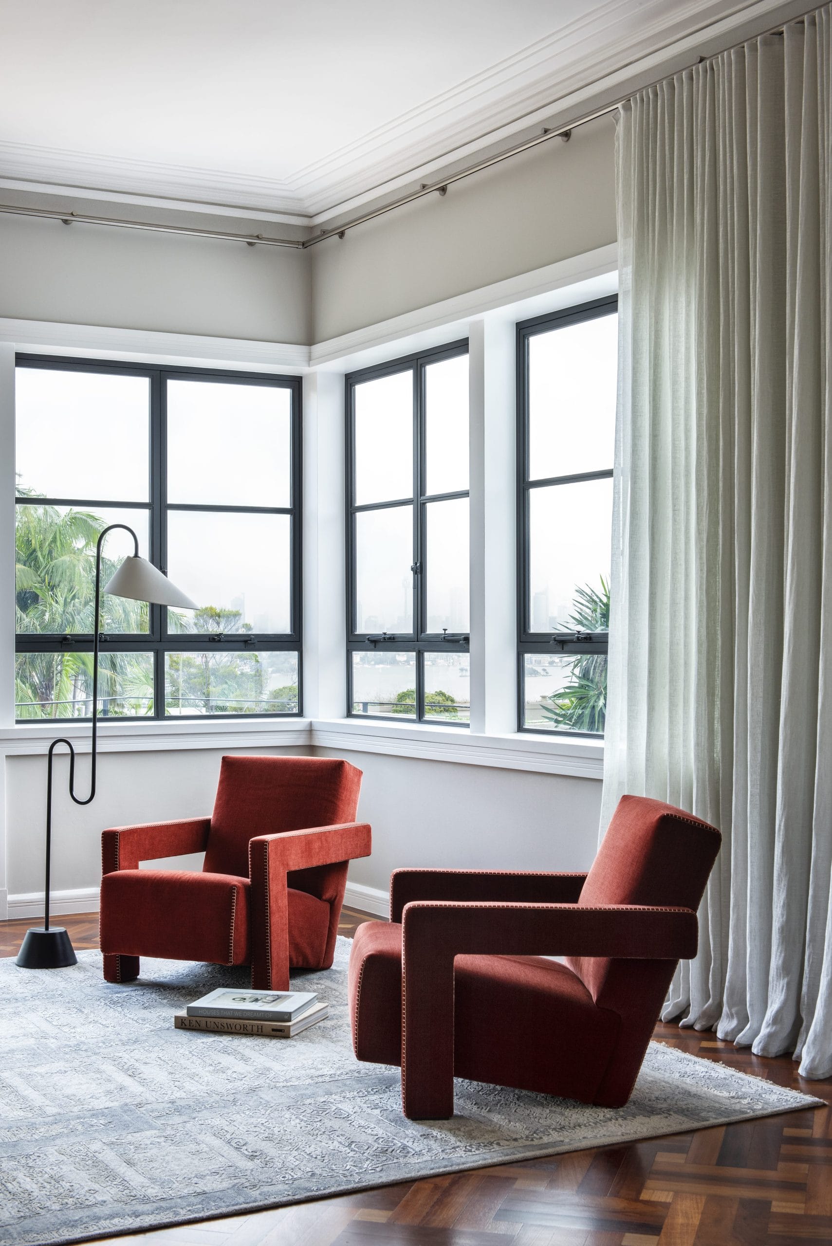 A living room featuring two retro chairs in burgundy overlooking Sydney harbour