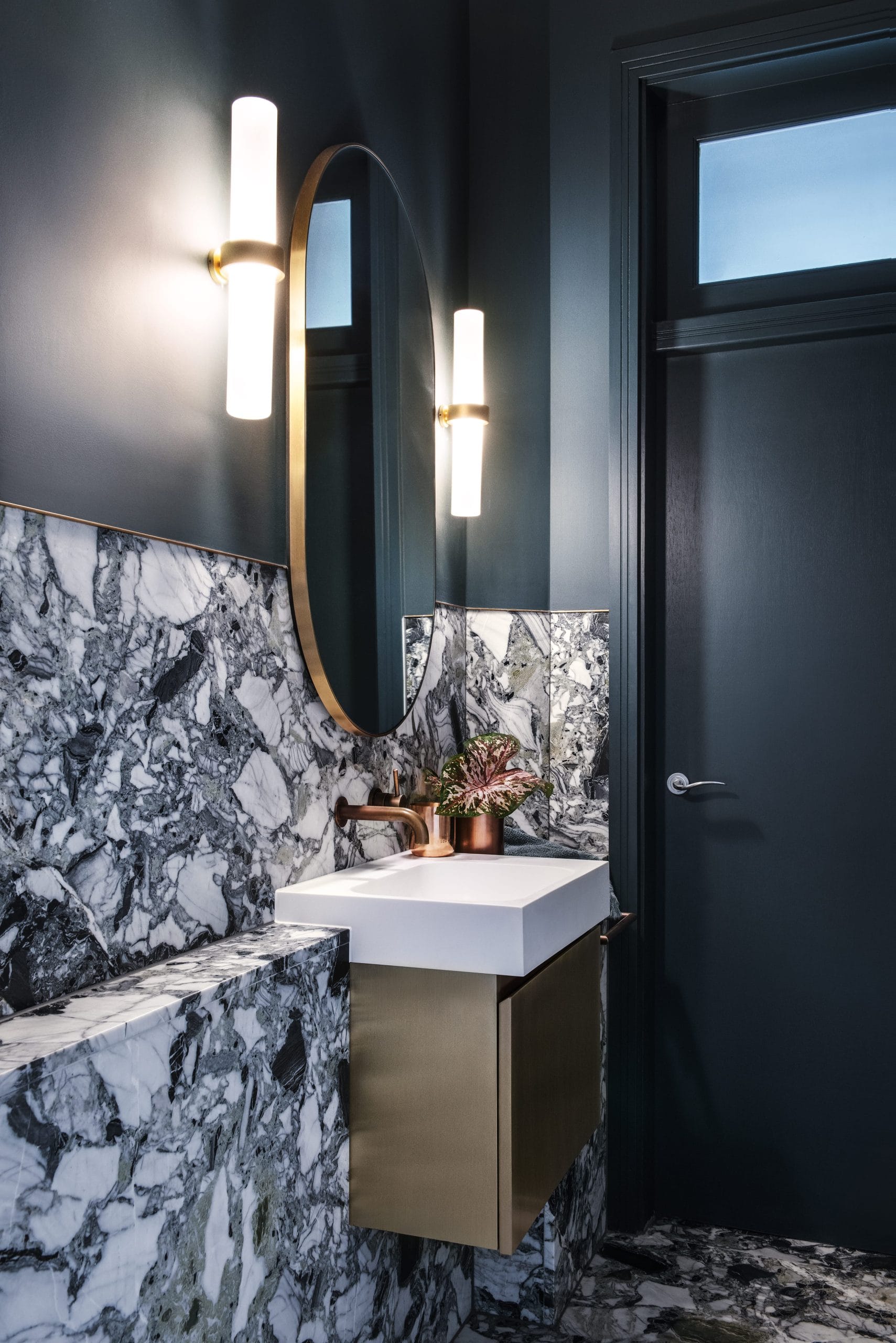 A modern bathroom with deep charcoal grey walls, stone accents and metallic finishes