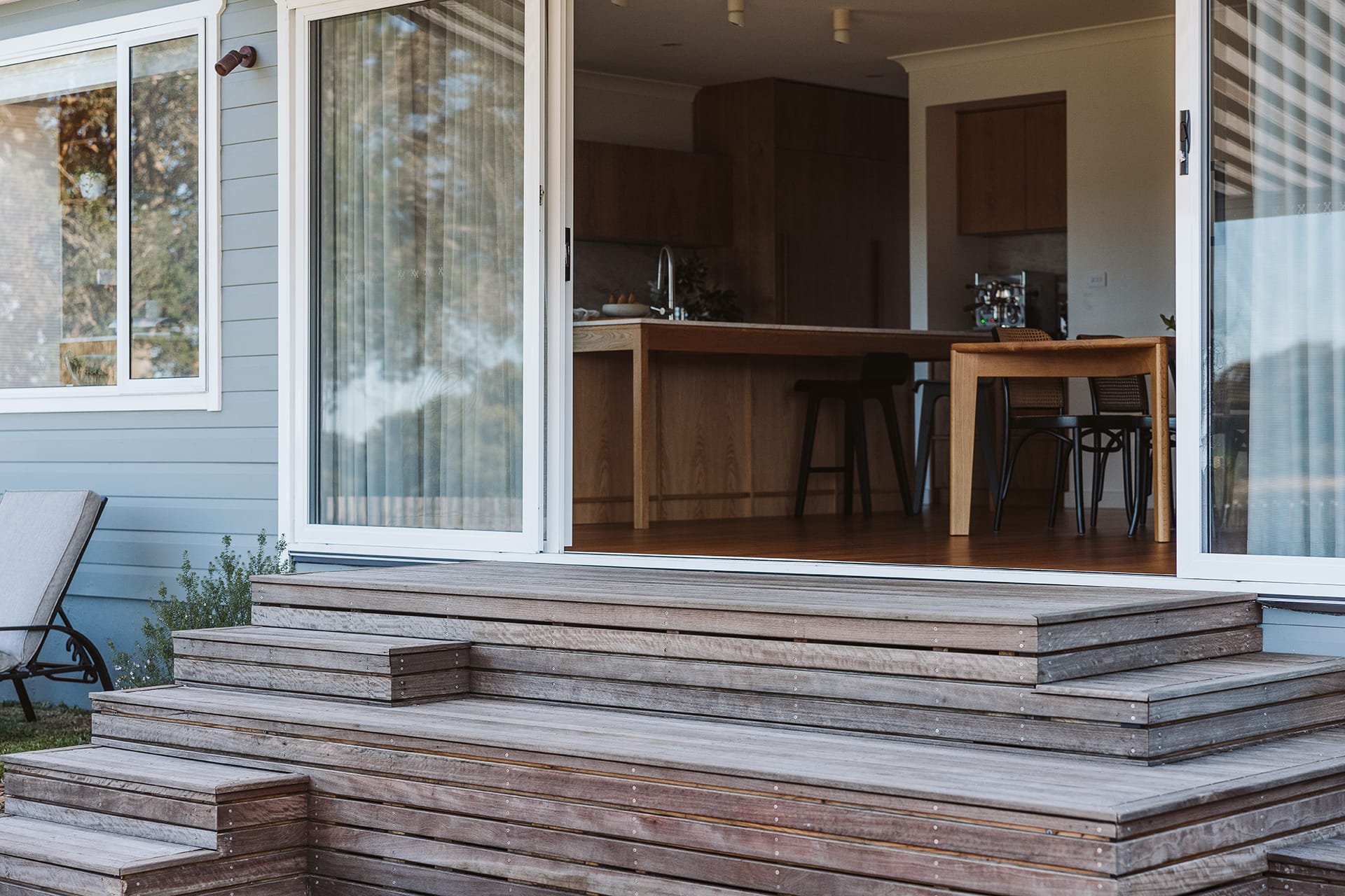 Sliding glass doors opening onto wide timber landing and steps by YourBuild Construct