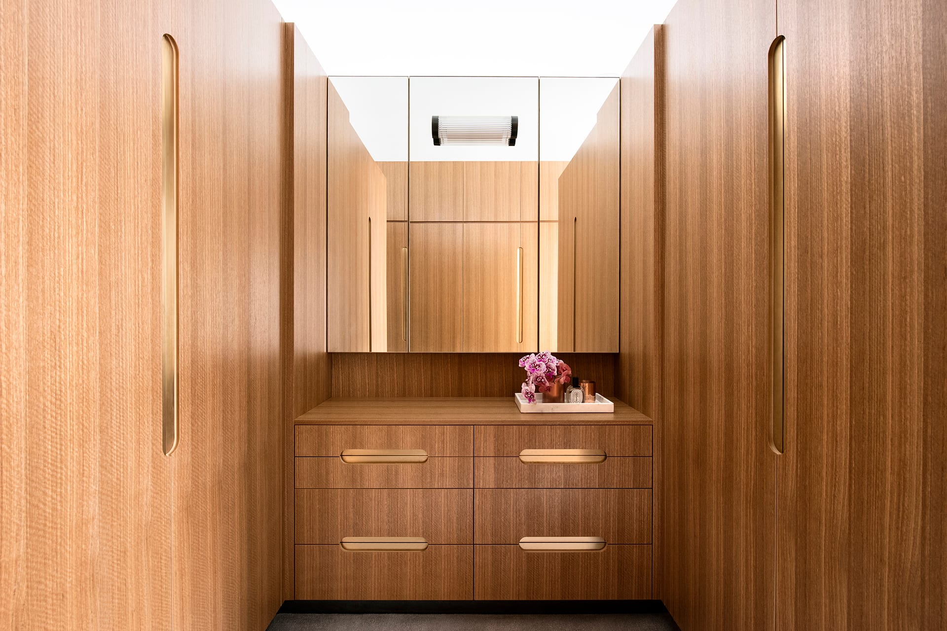 Timber walk in wardrobe cabinetry with metallic recessed handles