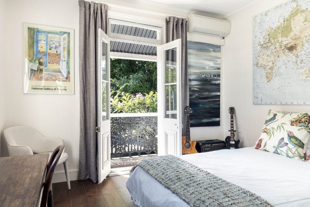 A bedroom in a renovated Paddington NSW terrace with French doors open to the verandah